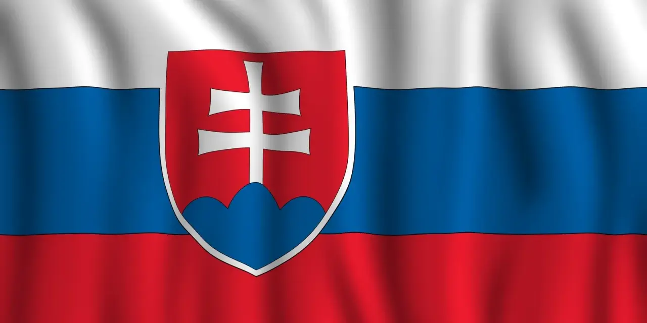 Flaga Słowacji powiewa na wietrze. Biało-niebiesko-czerwone pasy z godłem Słowacji po lewej stronie.