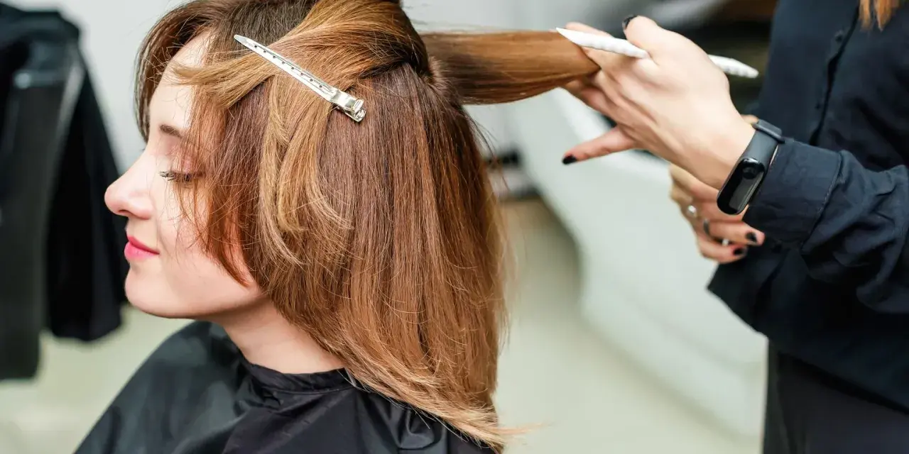 Fryzjerka modeluje włosy do ramion cieniowane, tworząc subtelne przejścia.