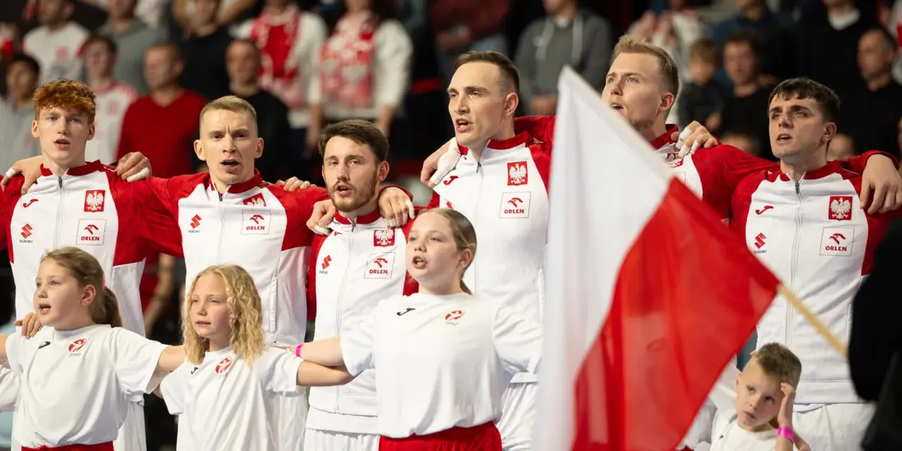 Polska drużyna piłki ręcznej z flagą narodową. Młodzi zawodnicy i dzieci w strojach biało-czerwonych.