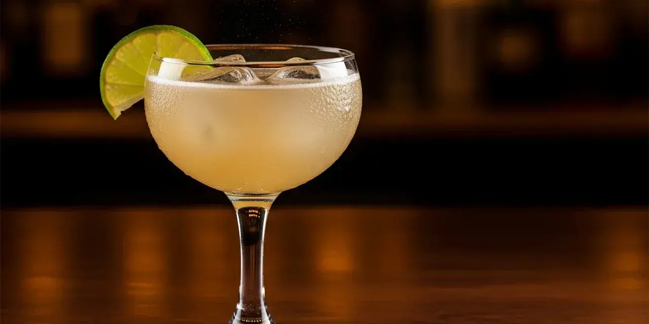 En kyld Moscow Mule med limeklyfta, is och bubblor på en träyta.