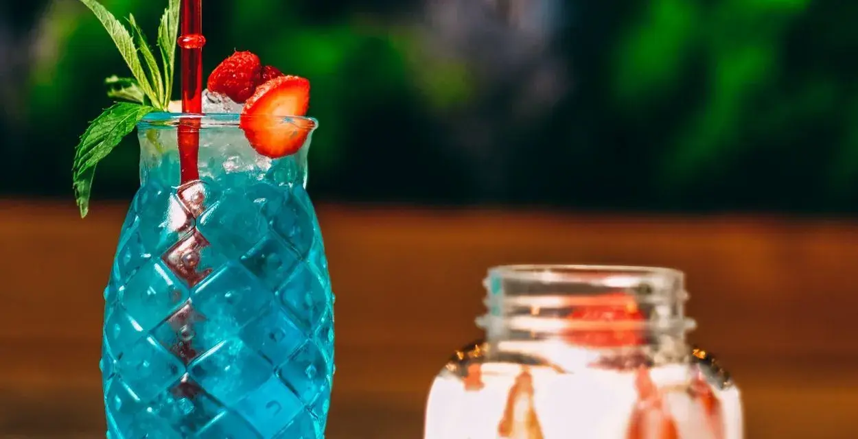 Orzeźwiający, niebieski drink z palemką, ozdobiony truskawką i miętą. Idealny na letnie popołudnie.