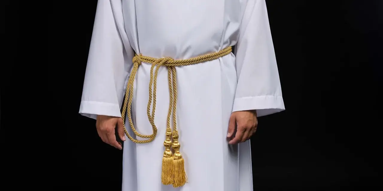 Szata proboszcza w kolorze białym, przepasana złotym sznurem z ozdobnymi chwostami.