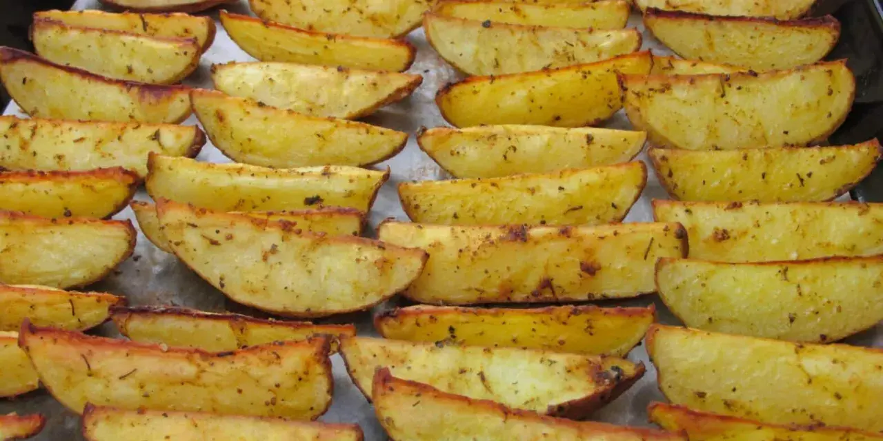 Des pommes de terre rôties au four croustillantes, dorées et assaisonnées, disposées sur une plaque de cuisson.