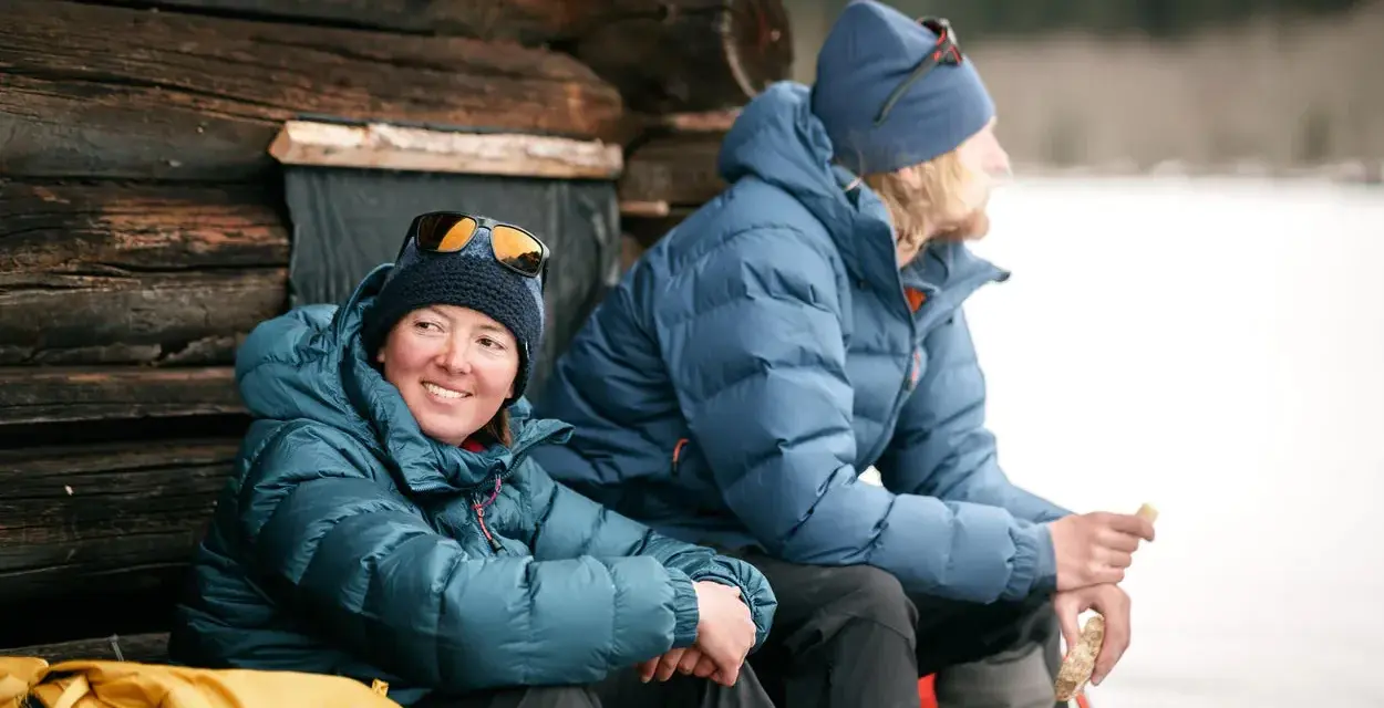 Zwei Personen in warmen 700 cuin Daunenjacken genießen eine Pause im Freien. Die Jacken halten sie bei kühler Temperatur angenehm warm.