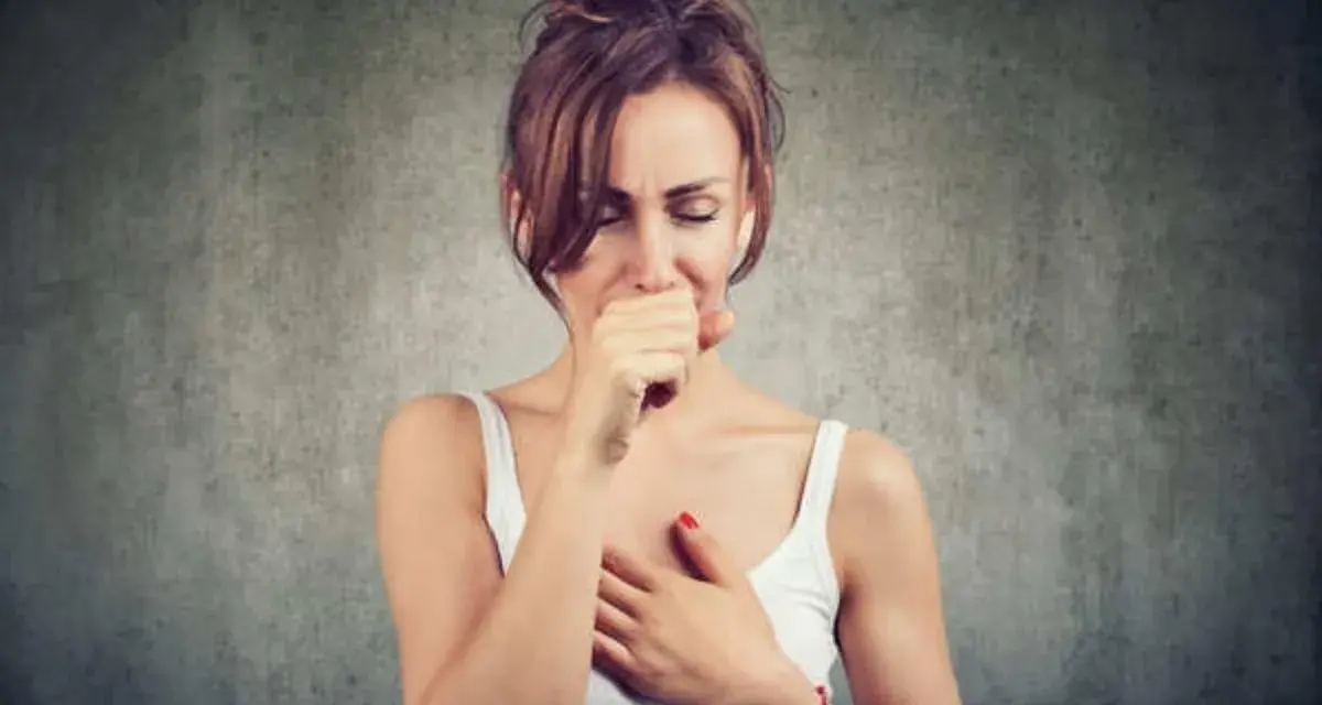 Mujer tosiendo y con dolor de cabeza, quizás por vapear.
