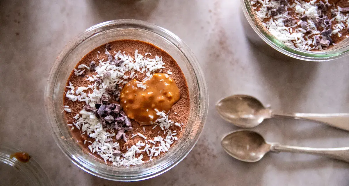 Chokladpudding med kokos och kakaonibs, en härlig proteinrik frukost. Två skedar ligger bredvid.