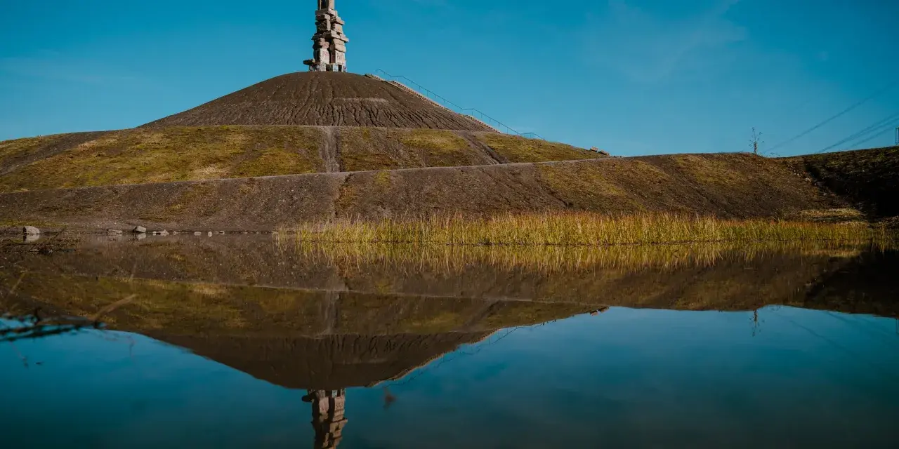 Die Himmelstreppe Gelsenkirchen spiegelt sich im Wasser. Ein Kunstwerk auf einer Halde.