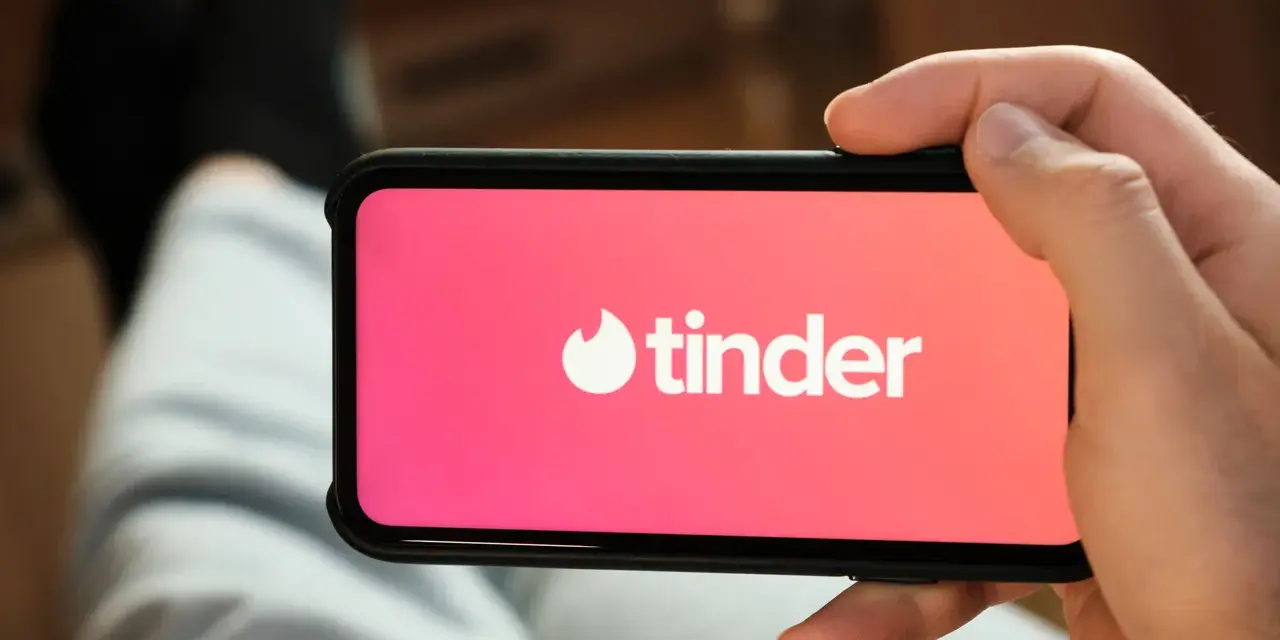 Dłoń trzyma smartfon z otwartą aplikacją do randkowania Tinder.