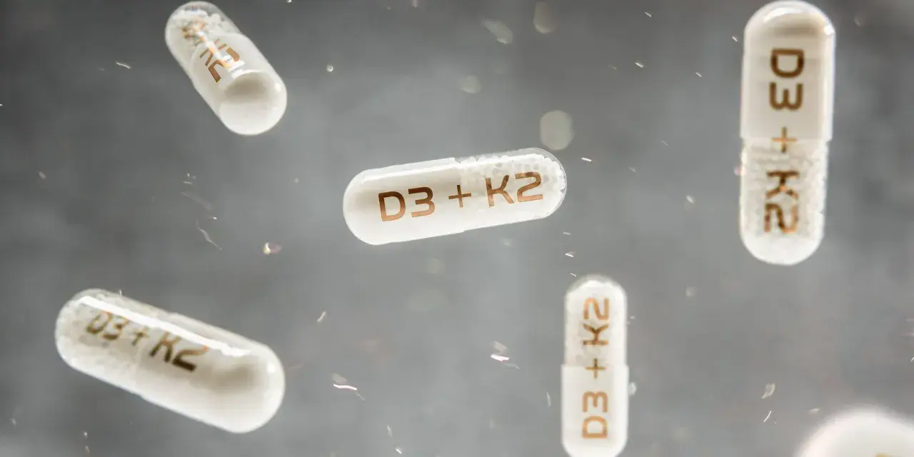 Flera kapslar med texten "D3 + K2" svävar i luften. Dessa kapslar kan vara ett komplement till din k vitamin mat.
