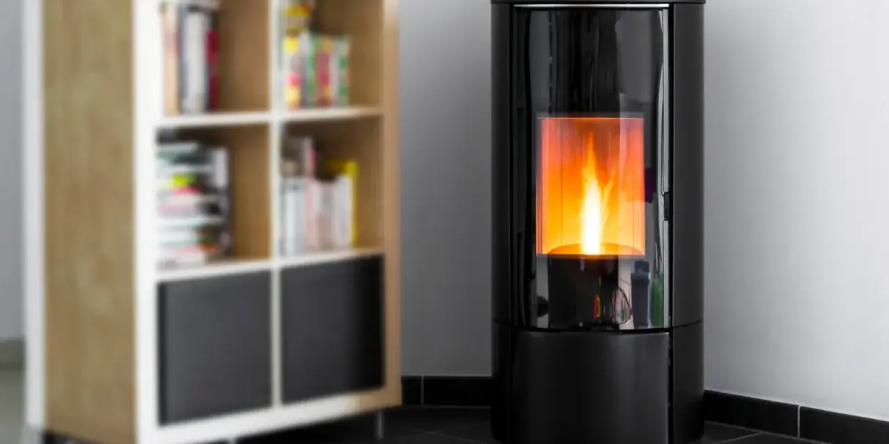 Stufa a pellet moderna in camera da letto, con fiamme vive che illuminano l'ambiente. Accanto, una libreria in legno con libri.