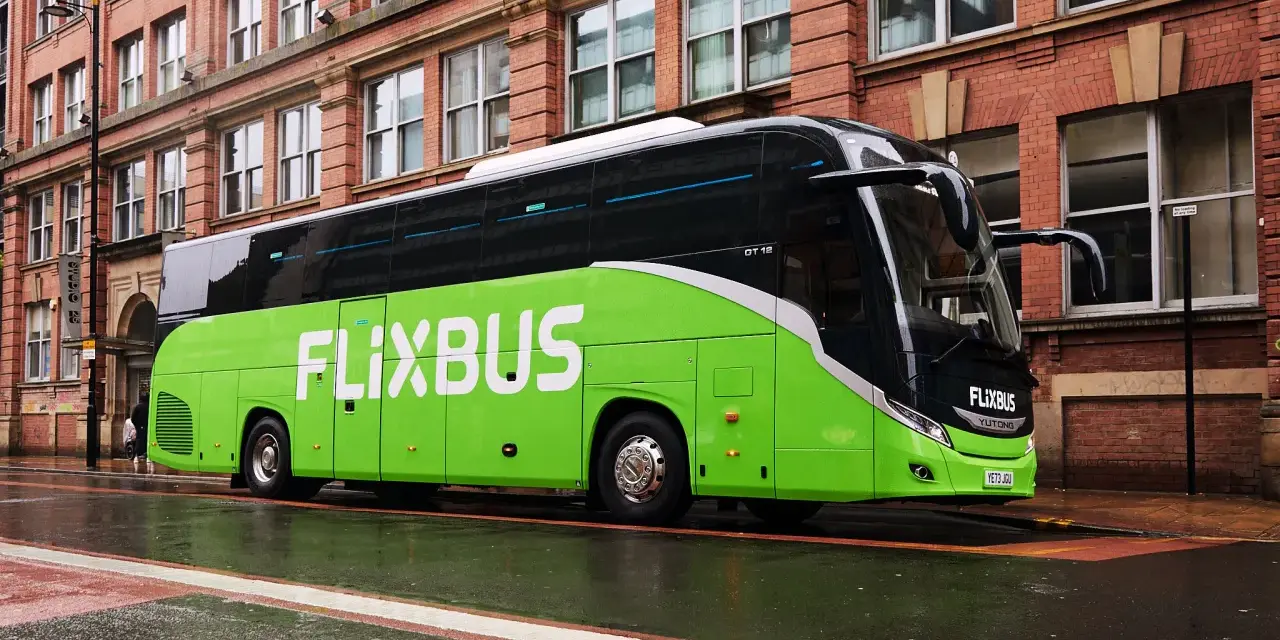 Zielony autokar FlixBus na mokrej ulicy. Wiele osób chwali sobie podróże tymi autobusami, a flixbus opinie są zazwyczaj pozytywne.