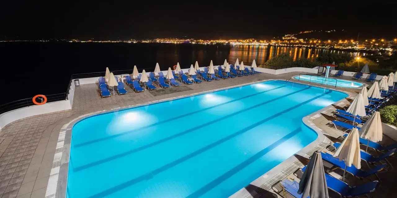 Basen hotelowy nocą, z widokiem na oświetlone miasto na horyzoncie. Idealne miejsce na relaks, jak sugerują pozytywne opinie o horizon beach.