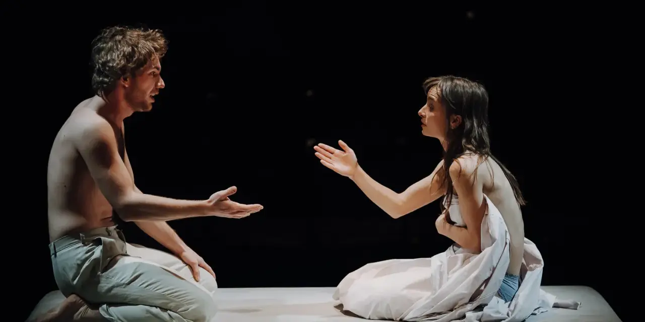 Aktorzy na scenie Teatru Narodowego, w intymnym geście, jakby dzielili się ostatnim tchnieniem.