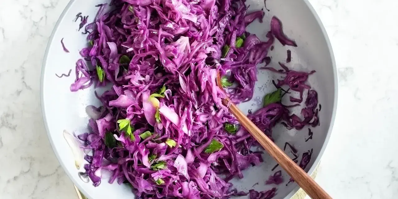Insalata fresca e colorata di cavolo cappuccio rosso, condita con erbe aromatiche, pronta per essere gustata.
