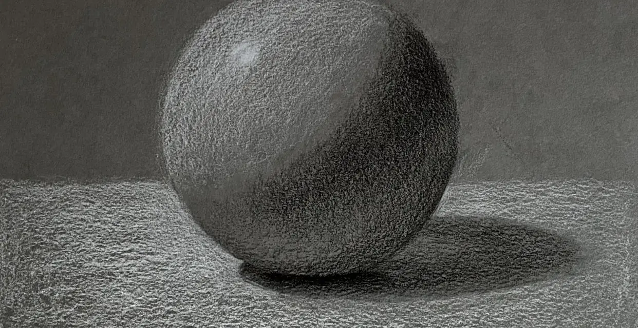 Un detallado dibujo a carboncillo de una esfera, con luces y sombras que le dan volumen. La textura del papel se aprecia en este estudio de esfera.