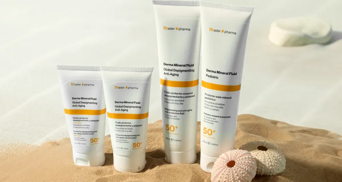 Cuatro tubos de crema solar biodegradable de Thader Pharma en la arena, con dos erizos de mar.