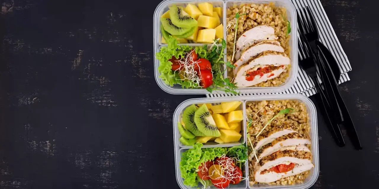 Dwa pudełka na lunch do pracy: kurczak faszerowany, kasza, sałatka z pomidorkami i kiełkami, kiwi i mango.