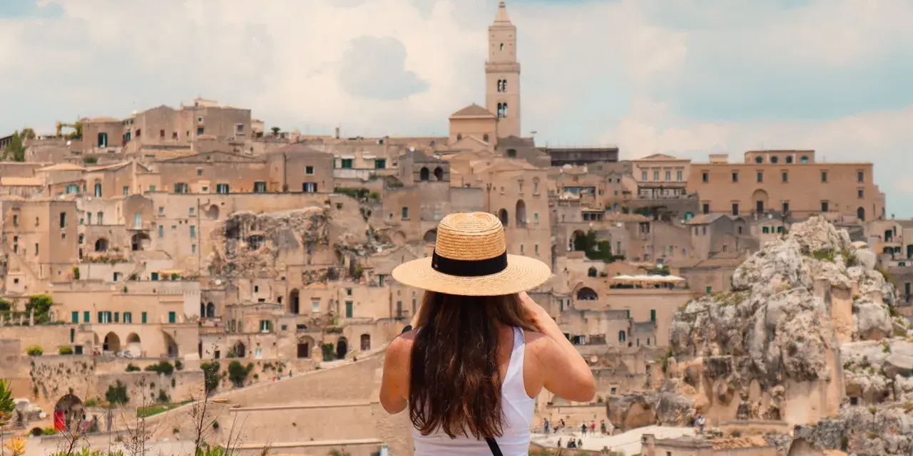 A woman in a straw hat captures the ancient city of Matera, a highlight of her southern tour of Italy.