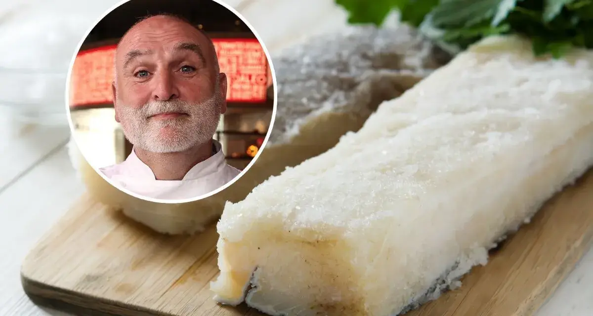 Chef sonriente junto a trozos de bacalao en salazón sobre tabla de madera.