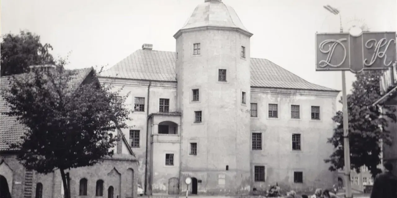 Zamek książąt pomorskich w Słupsku, z charakterystyczną wieżą i arkadowym balkonem, na tle miejskiego krajobrazu.