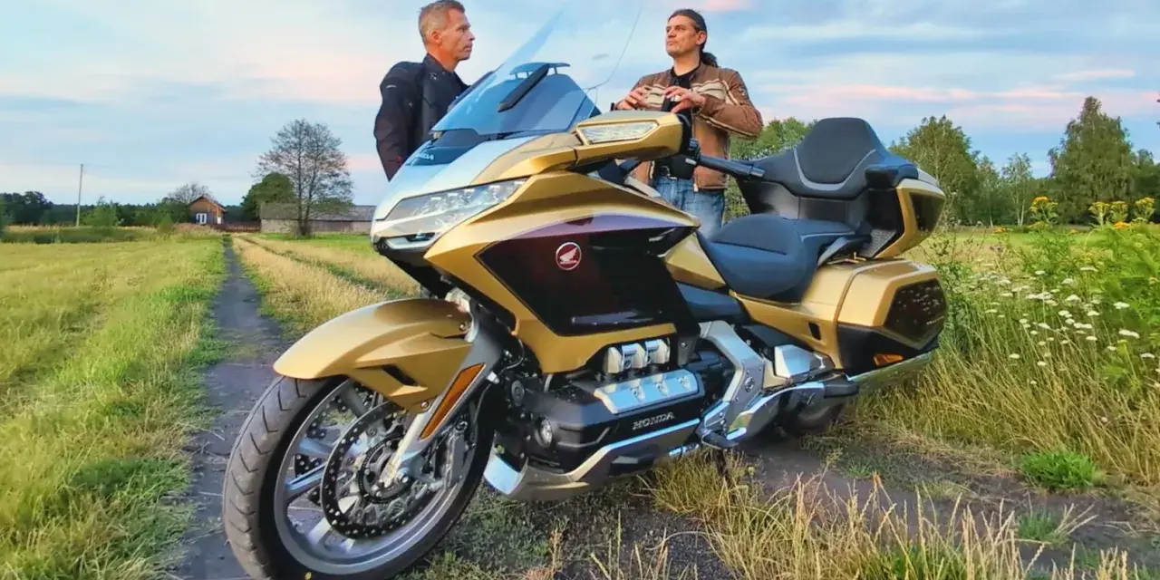 Złoty Honda Goldwing 1800 na polnej drodze, dwaj mężczyźni dyskutują o jego wadach.