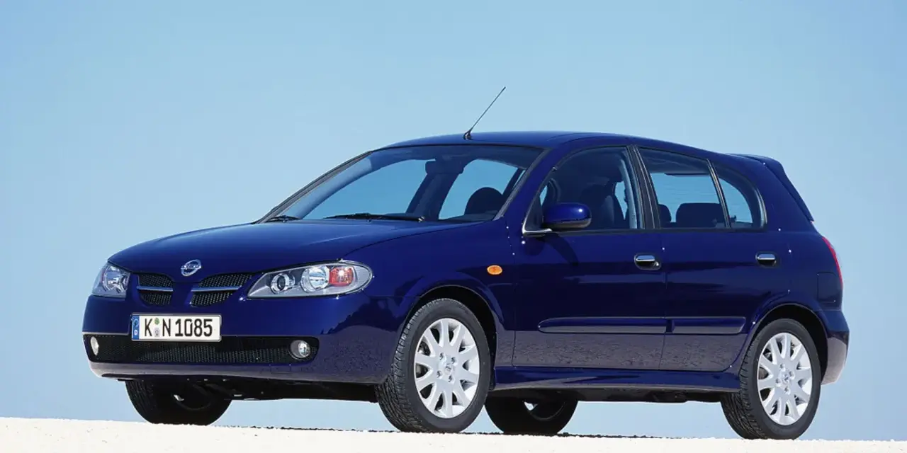 Granatowy Nissan Almera stoi na białym tle, z błękitnym niebem w tle.