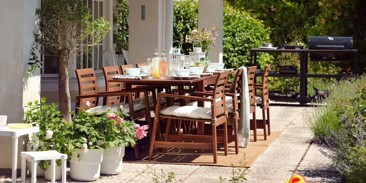 Gemütliche Terrasse mit Holztisch und Stühlen, perfekt, um die Terrasse gestalten mit wenig Geld. Grill und Pflanzen schaffen eine einladende Atmosphäre.