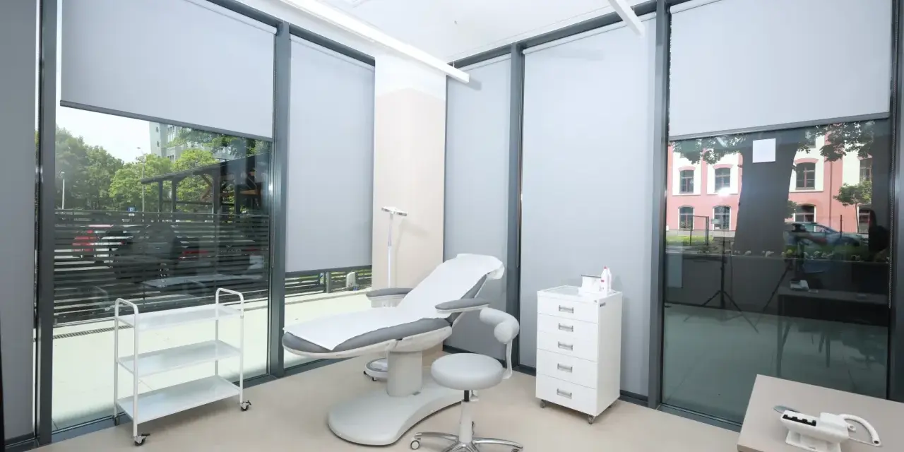 Gabinet dermatologiczny z fotelem zabiegowym, szafką i wózkiem.