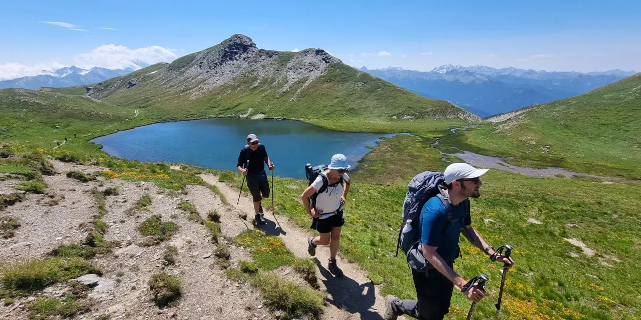 Trois randonneurs progressent sur un sentier de montagne, profitant d'un paysage spectaculaire. Ils sont en plein tour du Queyras 4 jours.