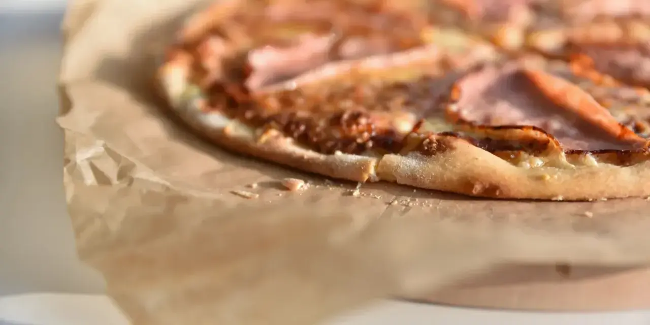 Apetyczna pizza na papierze do pieczenia. Zastanawiasz się, ile kcal ma pizza 40 cm? Ta wygląda na pyszną!