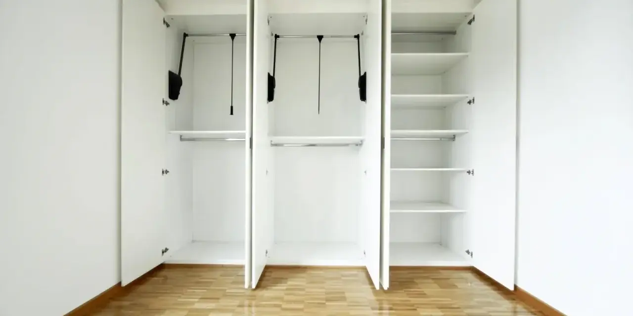 Interno di un armadio bianco a tre ante, vuoto, con ripiani e barre appendiabiti. Un esempio di come costruire un armadio funzionale.