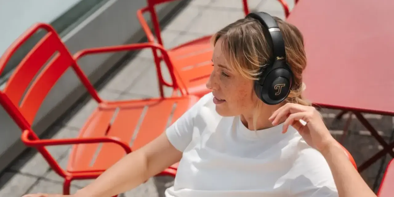 Femme aux taches de rousseur écoutant de la musique avec des écouteurs, un exemple de 85 dB pour une immersion sonore.