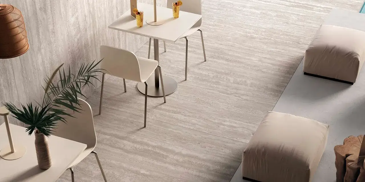 Un caffè moderno con tavolini, sedie e pouf, su eleganti pavimenti senza fughe effetto pietra.