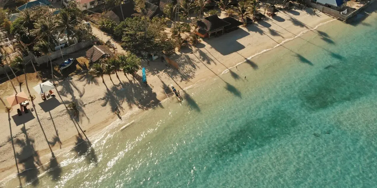 Tropikalna plaża z palmami i turkusową wodą. Idealne miejsce na wakacje, zastanawiasz się, ile trwa lot na Filipiny?