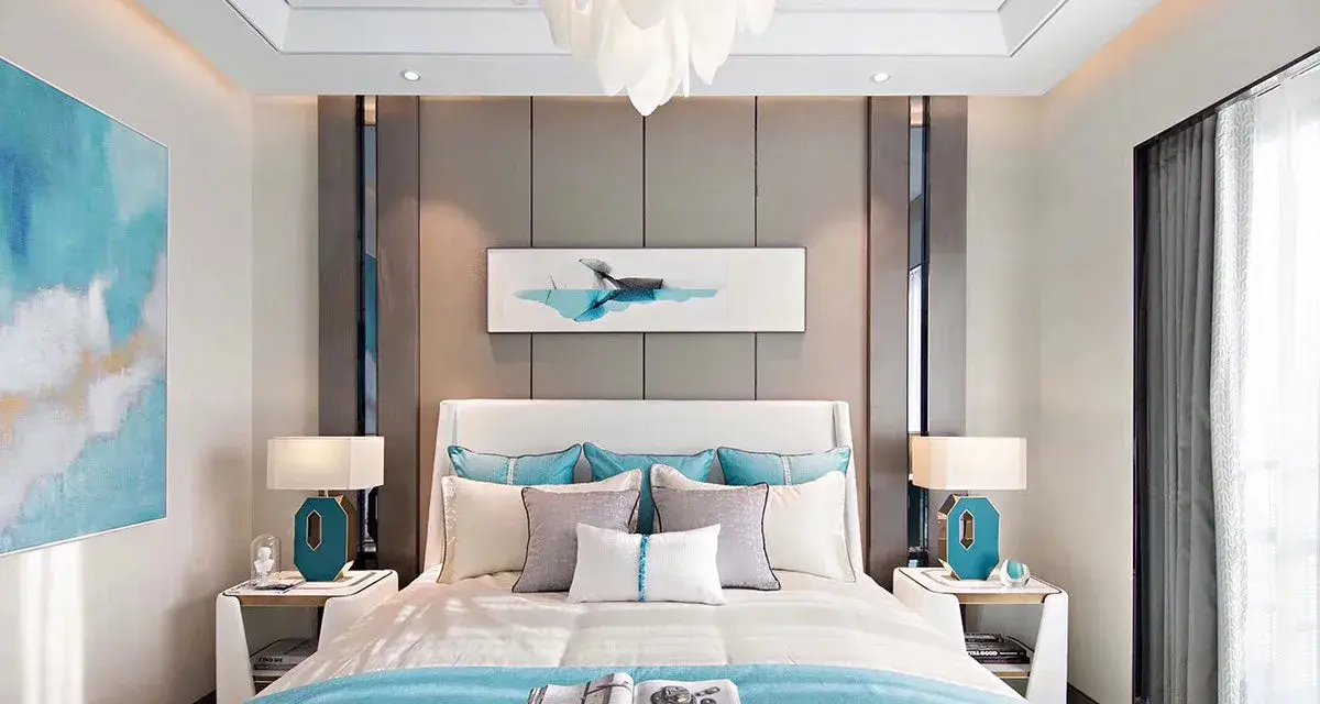 Elegante camera da letto casa al mare con quadri a tema acquatico, biancheria azzurra e lampade moderne.