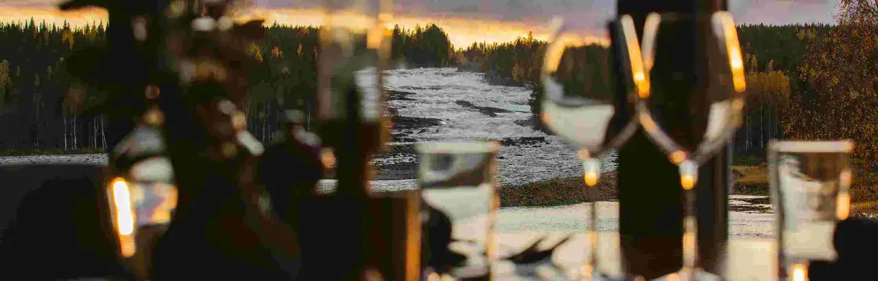 Storforsen camping: en brusande fors i solnedgången, med skog och träd som ramar in. Mysig belysning i förgrunden.