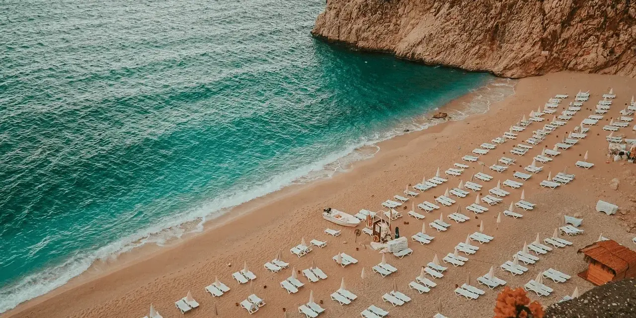 Piękna plaża z leżakami i turkusową wodą. Idealne miejsce, by zapytać: Turcja gdzie na wakacje?