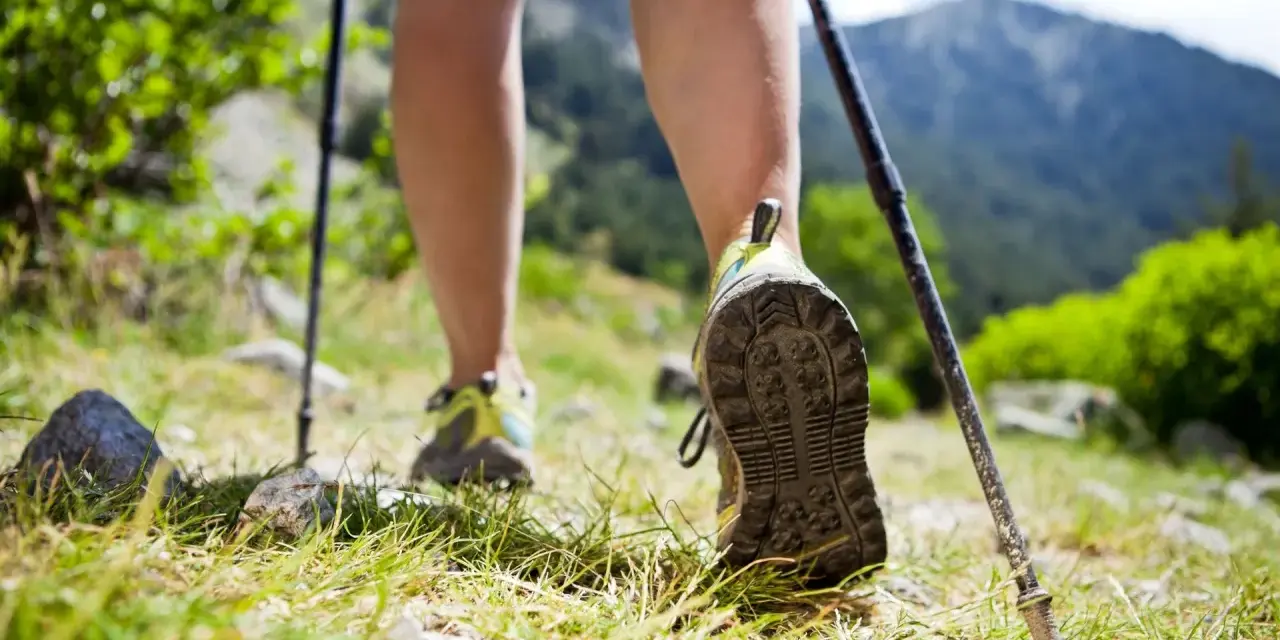 Nauka jak chodzić z kijkami to klucz do stabilności na górskim szlaku. Widok na nogi w butach trekkingowych i kijki wspierające marsz.