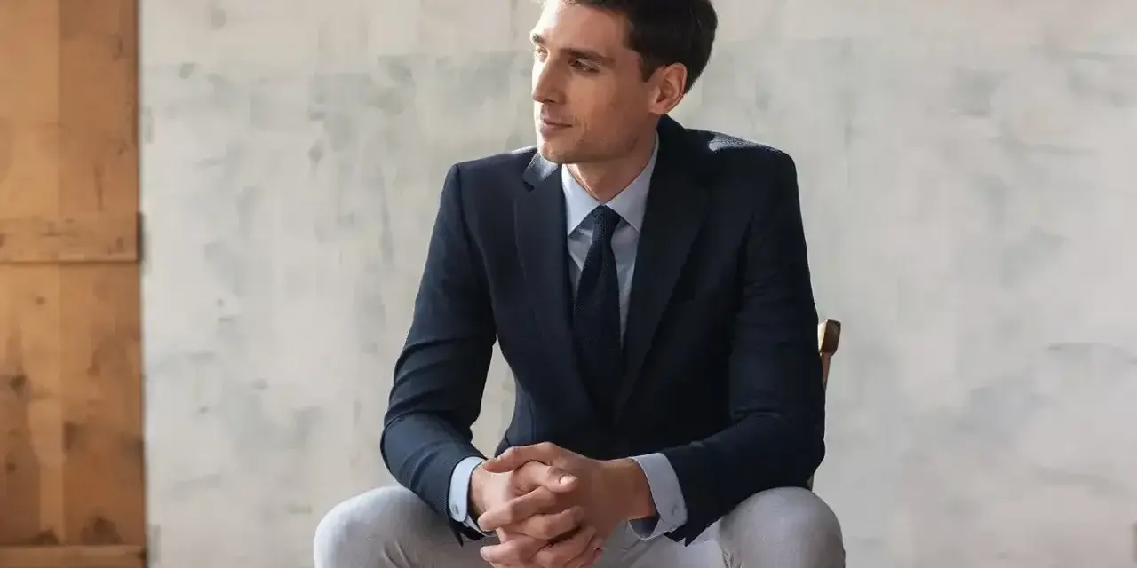 Elegancki mężczyzna w granatowej marynarce i jasnych spodniach. Idealne połączenie, jeśli zastanawiasz się, jakie spodnie do granatowej marynarki pasują.