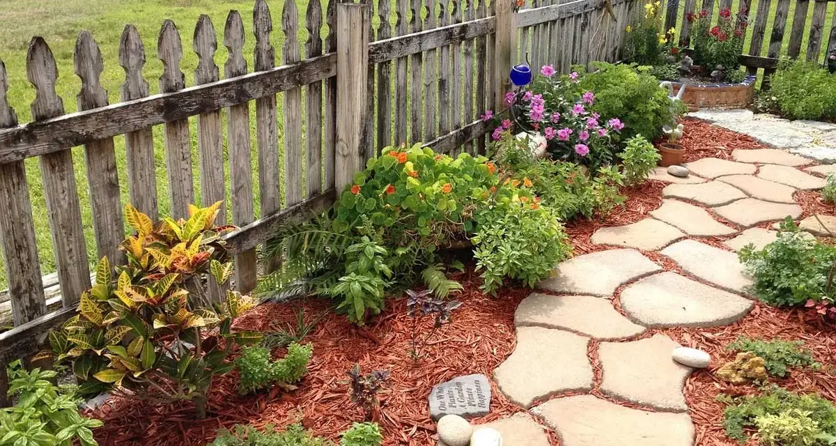Natürliche Steinplatten formen einen geschwungenen Gartenweg, umgeben von bunten Blumen und grünen Pflanzen. Tolle Gartenweg Ideen für ein idyllisches Zuhause.