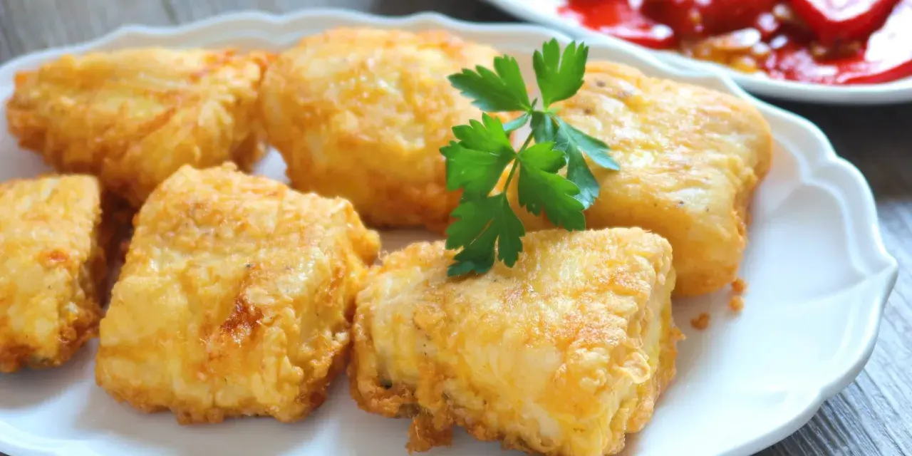 Crujientes trozos de merluza a la romana, dorados y listos para disfrutar. Un clásico plato español.
