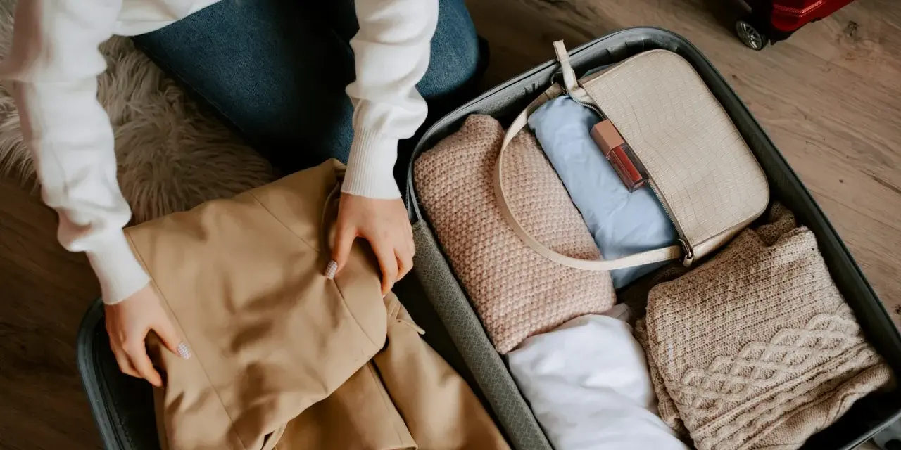 Pakowanie walizki. Zastanawiasz się, ile kosztuje dokupienie bagażu rejestrowanego Ryanair? W środku ubrania, torebka i kosmetyki.