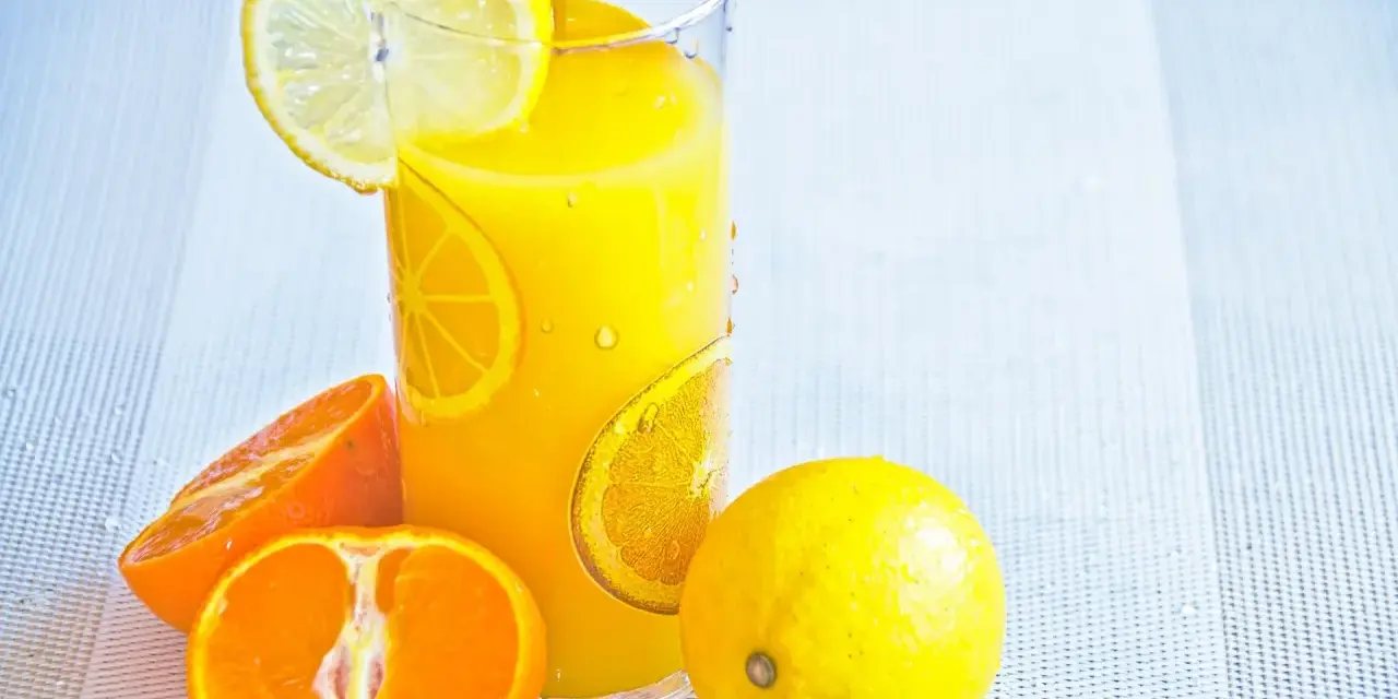 Succo d'arancia e limone, ricchi di vitamina C, in un bicchiere con fette di agrumi.