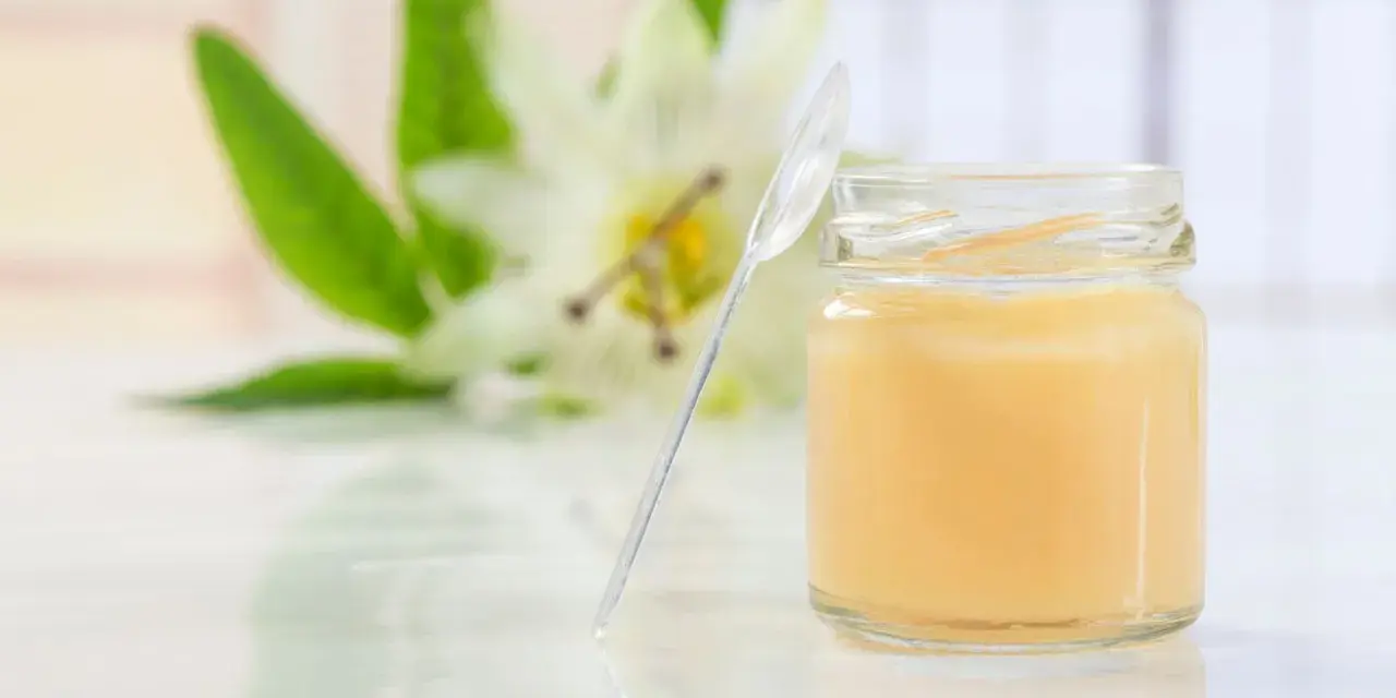 Un vasetto di pappa reale, con un fiore sullo sfondo. Alcuni credono che la pappa reale fa ingrassare, ma è un alimento nutriente.