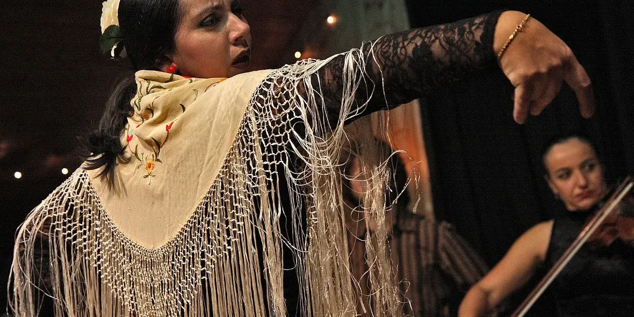 Tancerka flamenco z frędzlami na szalu, w tle skrzypaczka. To jest co to flamenco.