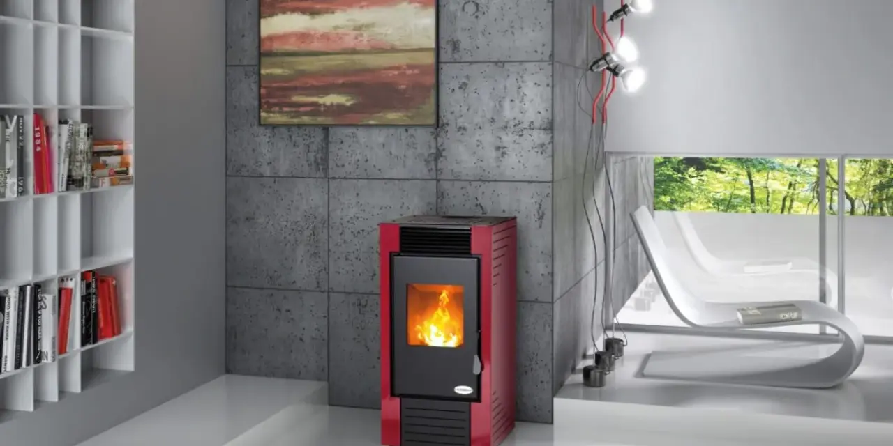 Estufa roja moderna con fuego encendido, mostrando cómo funciona la biomasa. Estantería blanca con libros y sillones blancos al fondo.