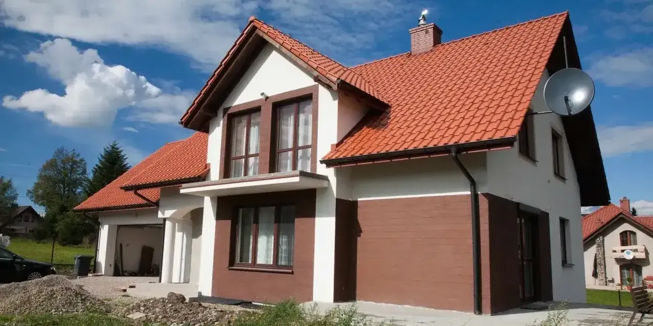 Jaki kolor elewacji do czerwonego dachu? Biała elewacja z brązowymi akcentami, jak na tym domu, wygląda stylowo.