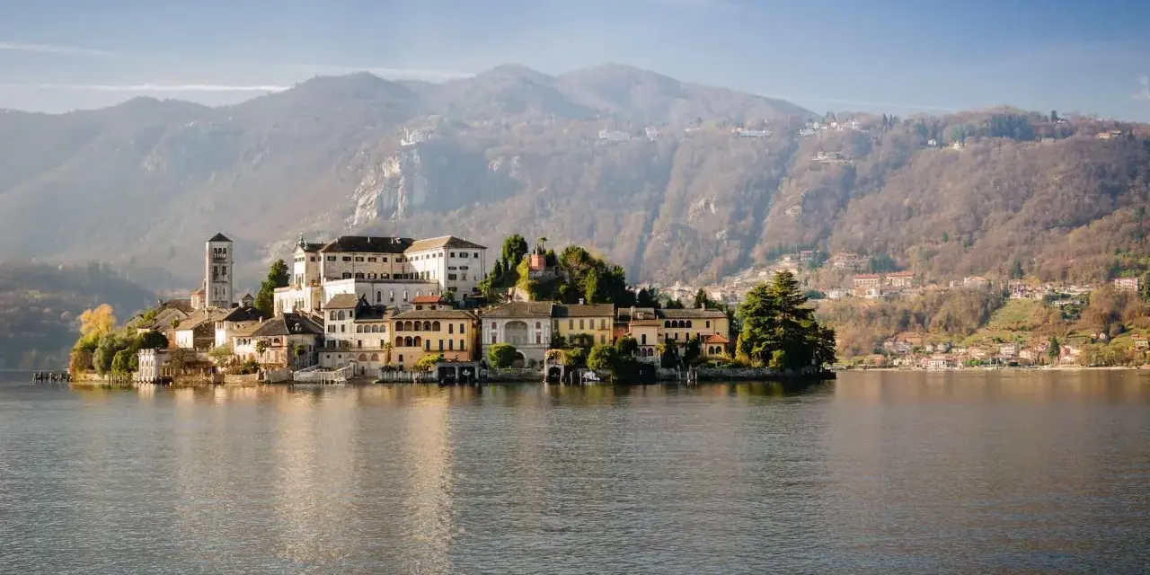Isola di San Giulio, uno dei più bei posti da visitare in Piemonte, con il suo borgo antico sul lago d'Orta e le montagne sullo sfondo.