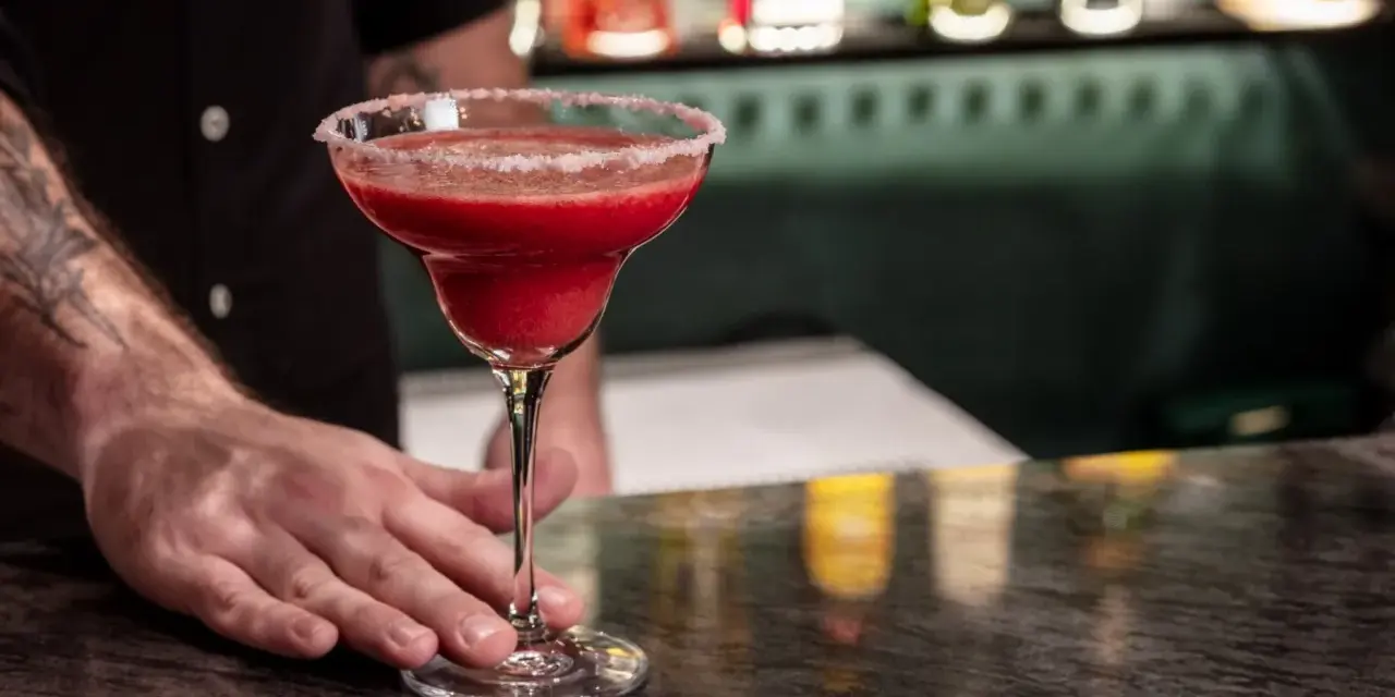 Margarita klasyczna kontra Margarita truskawkowa. Barman podaje orzeźwiającą, mrożoną truskawkową Margaritę z solą na brzegu kieliszka.