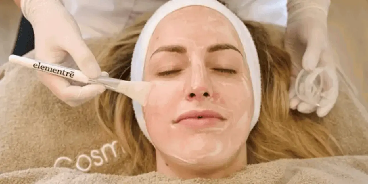 Kosmetikerin trägt eine Maske auf, um die Haut zu reinigen.